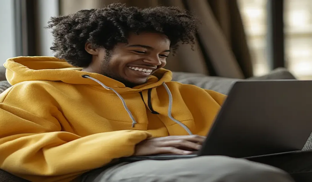 A person happily working on a laptop in a modern workspace, symbolizing online marketing success and financial independence